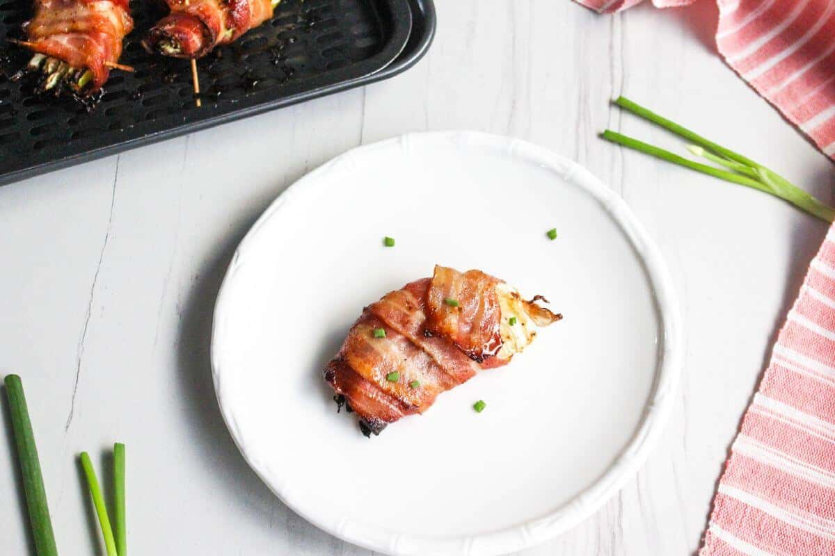 Bacon wrapped air fryer cabbage on white plate.