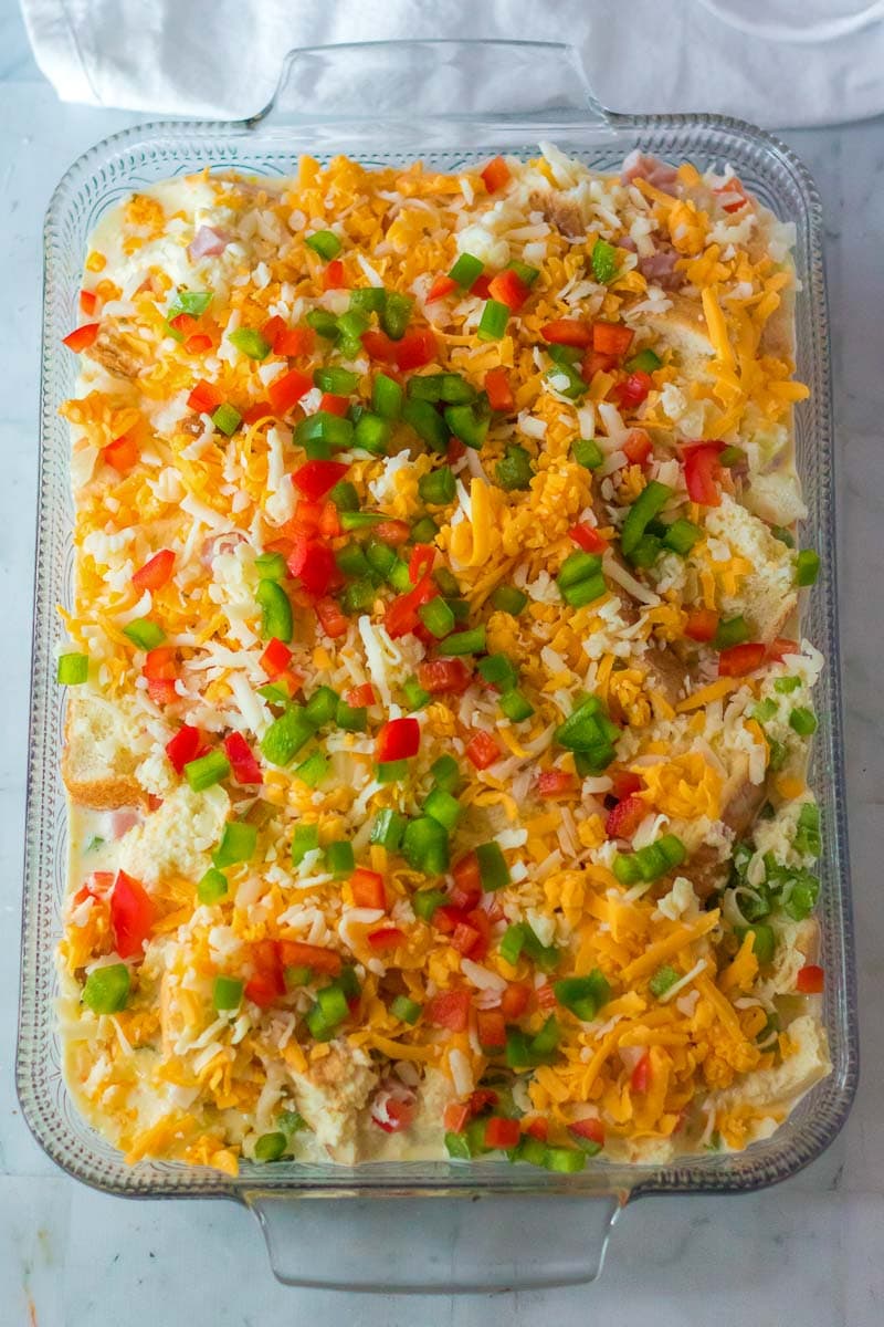 A Christmas breakfast casserole dish filled with shredded cheese and peppers.