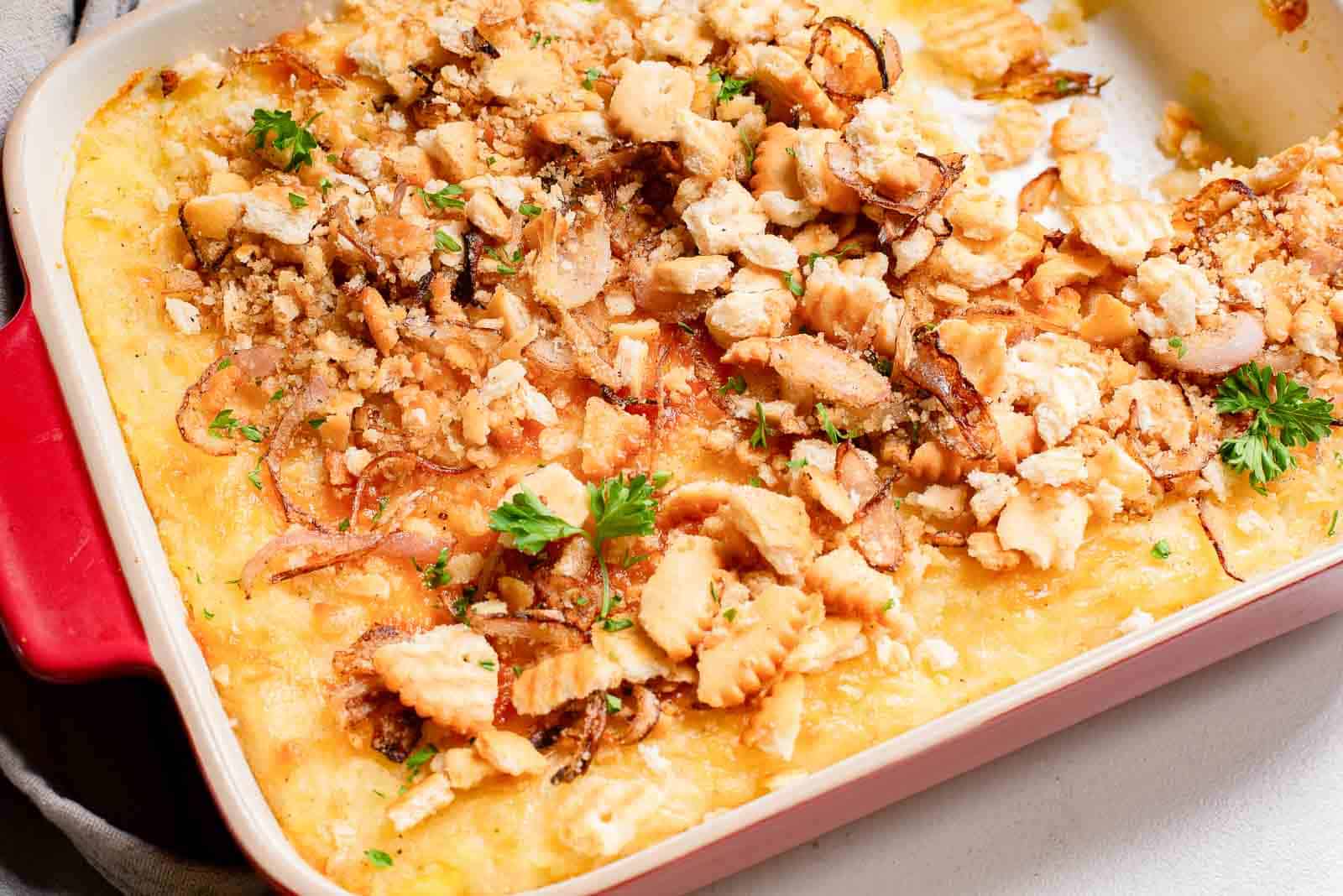 Masshed potato casserole in a baking dish with a cracker crumb topping.