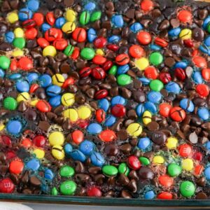 chocolate dump cake with M&Ms on top in a glass baking dish.
