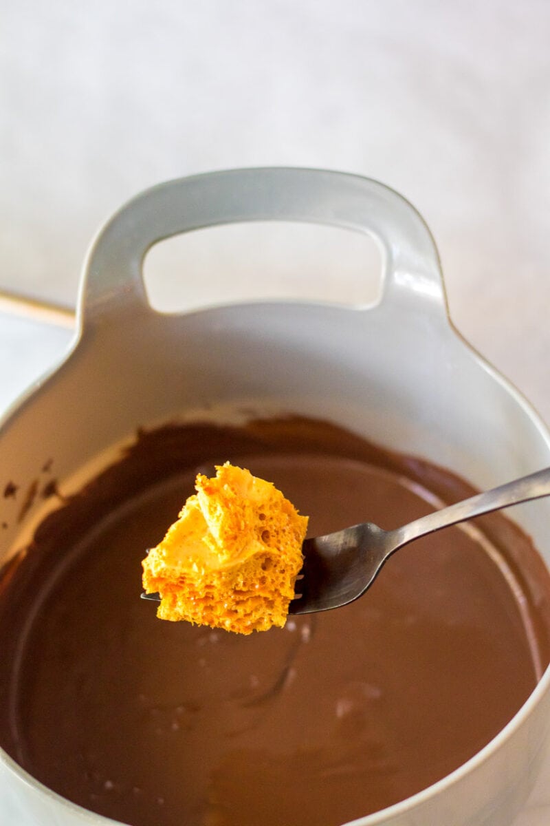 A spoon is holding a piece of chocolate in a pot.