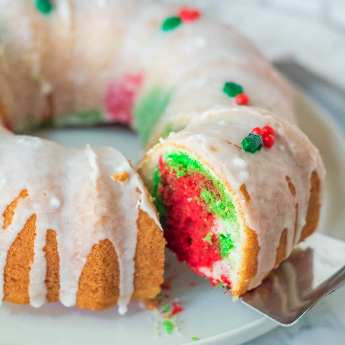 A festive Christmas bundt cake on a plate with a generous drizzle of icing.