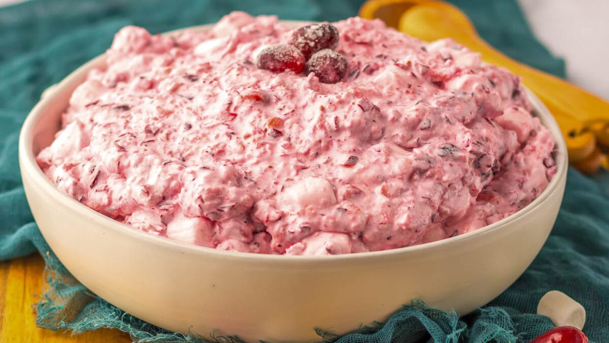 A bowl of pink cranberry dip with a wooden spoon.