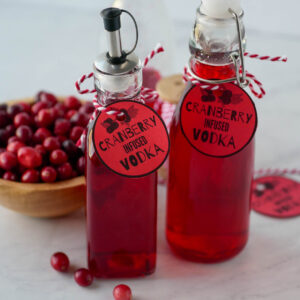 Two bottles of cranberry vodka with tags on them.