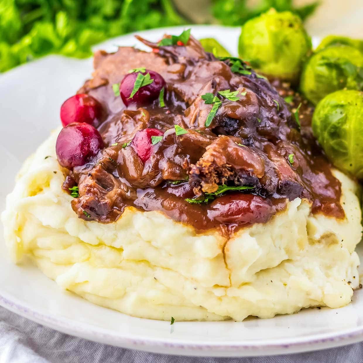 A plate with mashed potatoes, gravy and brussels sprouts.
