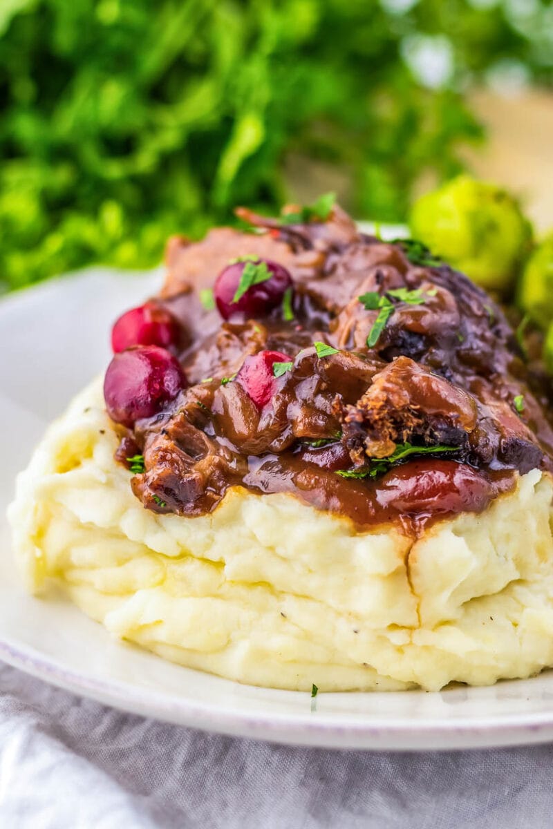 A plate of mashed potatoes with cranberry sauce and brussels sprouts.
