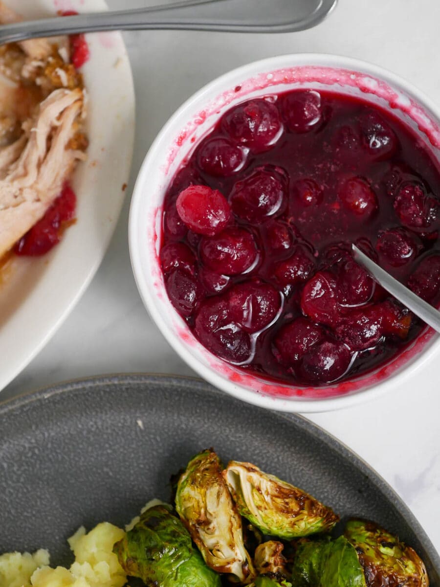 A plate with turkey, brussels sprouts and cranberry sauce.