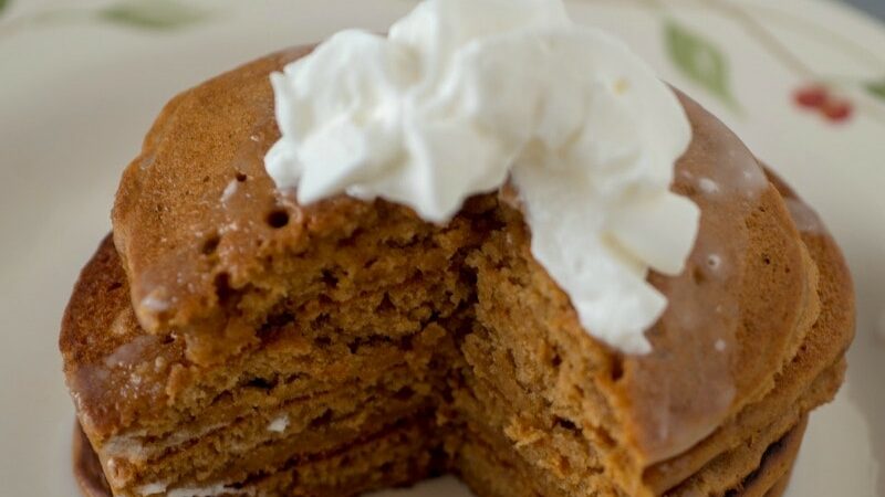 Stack of gingerbread pancakes with whipped cream.