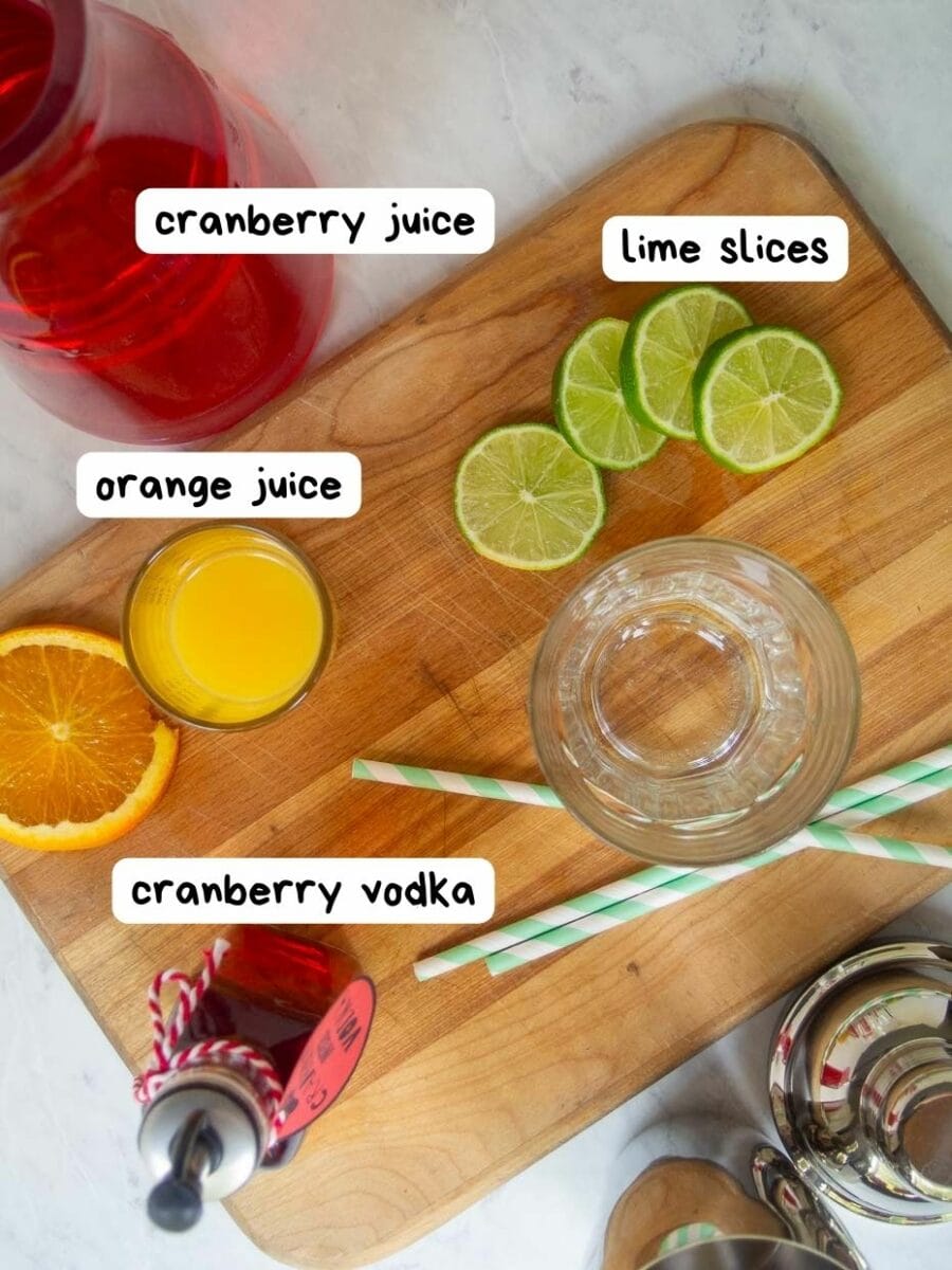 The ingredients for a cranberry juice cocktail on a cutting board.