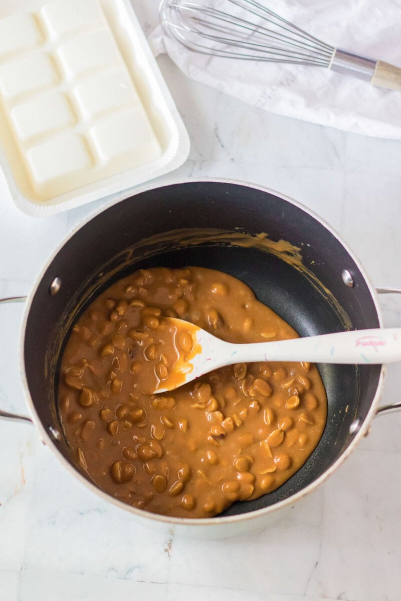 A pan filled with caramel beans and a spatula.