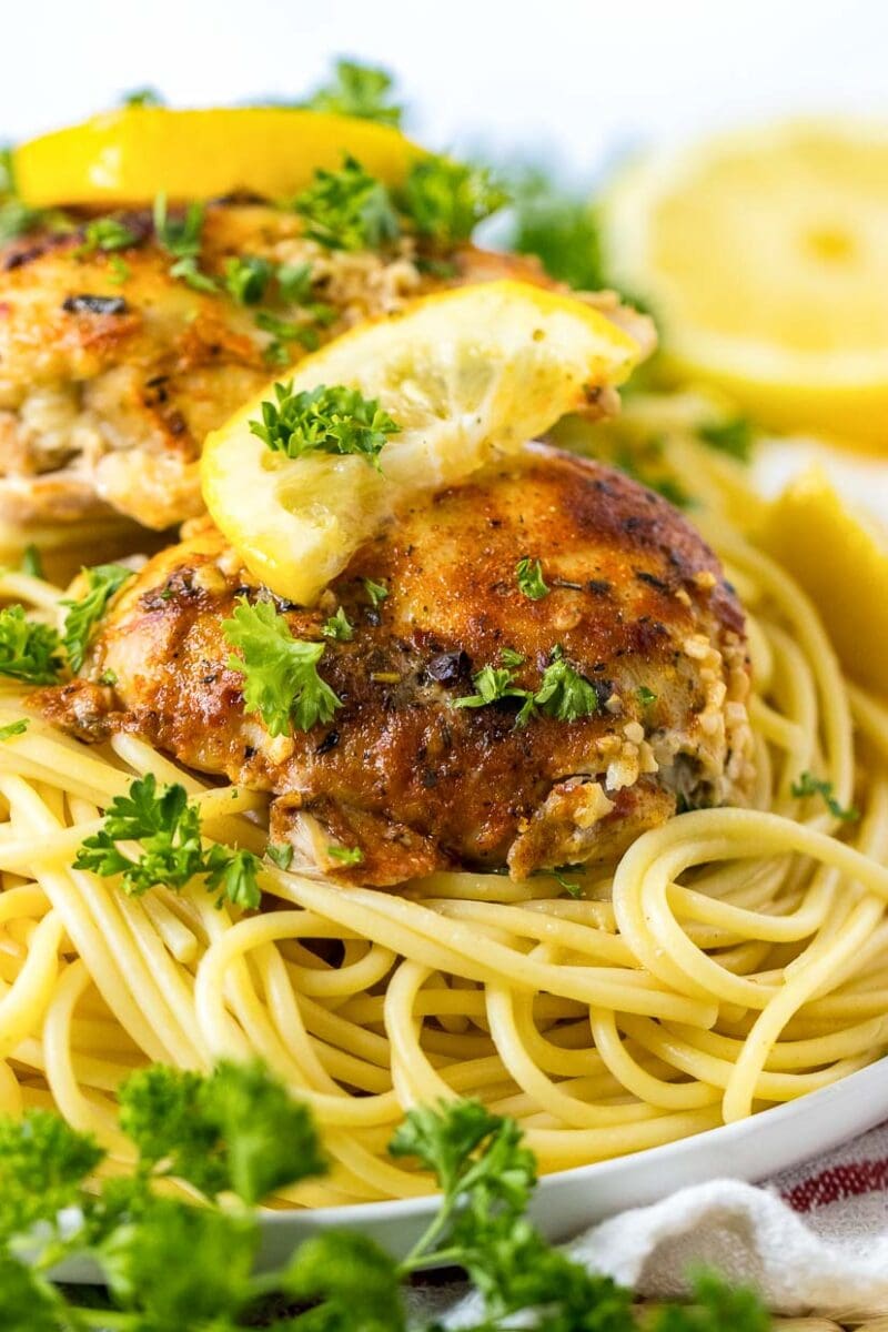 A plate of spaghetti with chicken and lemon on it.