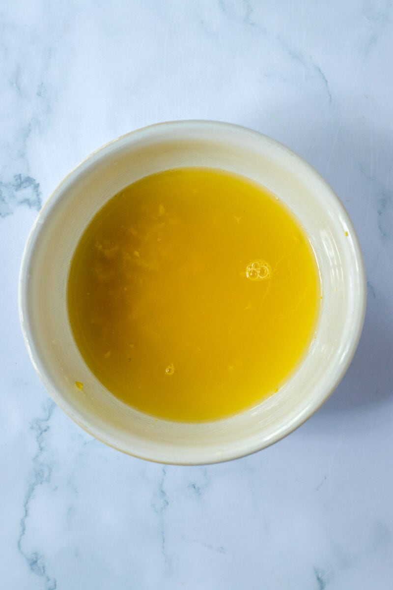 A bowl of yellow liquid on a marble surface.