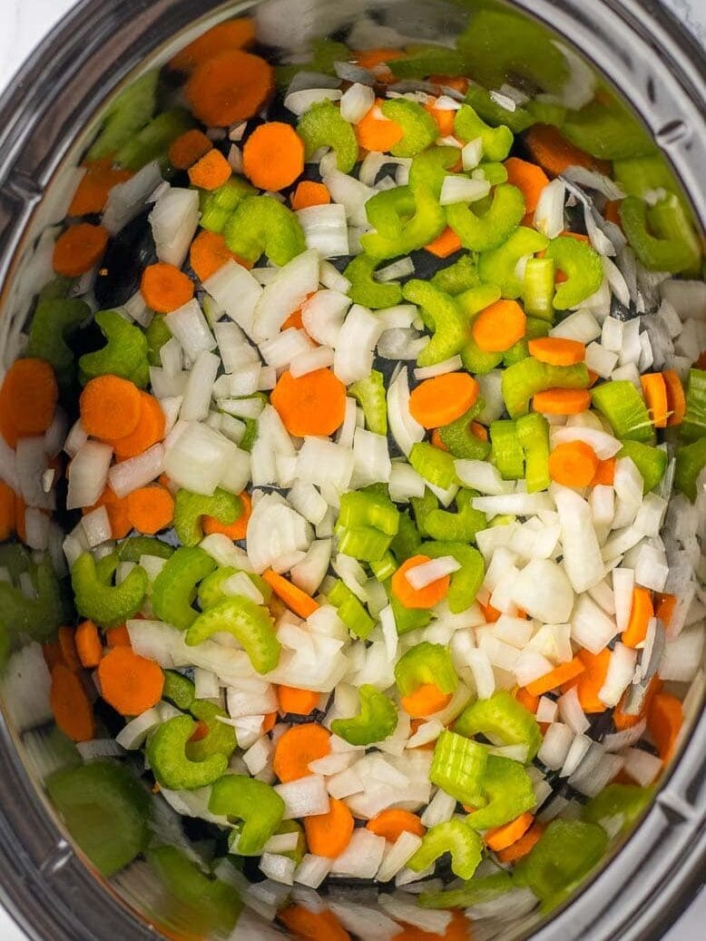 Chopped carrots and onions in a crock pot.