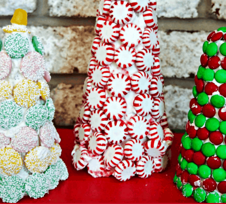 Three candy cane christmas trees on a red table.