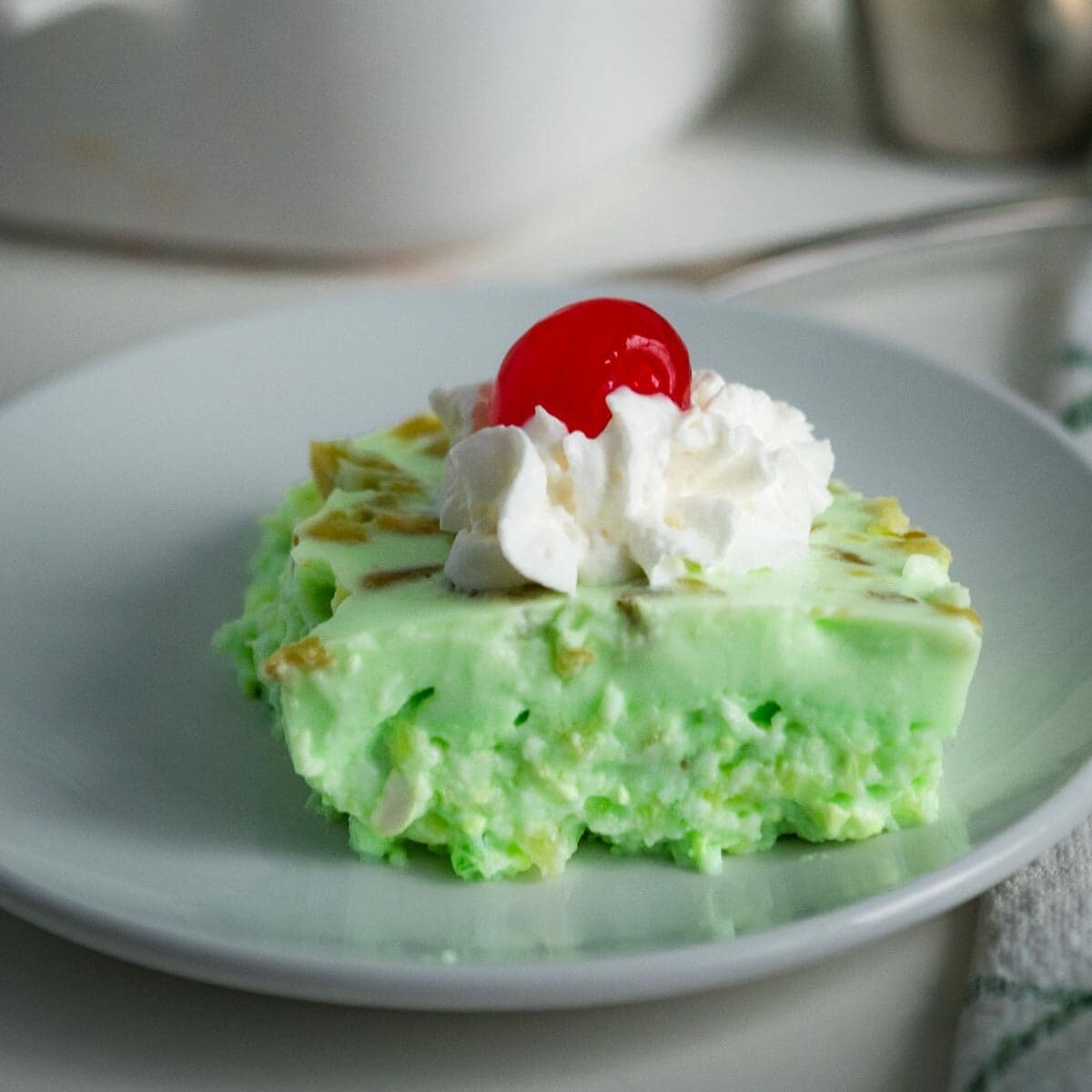 green jello salad topped with whipped cream and a cherry.