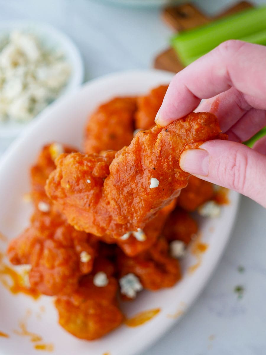 Buffalo wings on a plate with celery and blue cheese.
