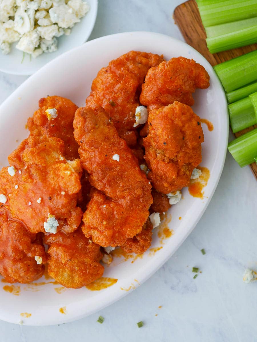 Buffalo wings on a plate with celery and celery sticks.