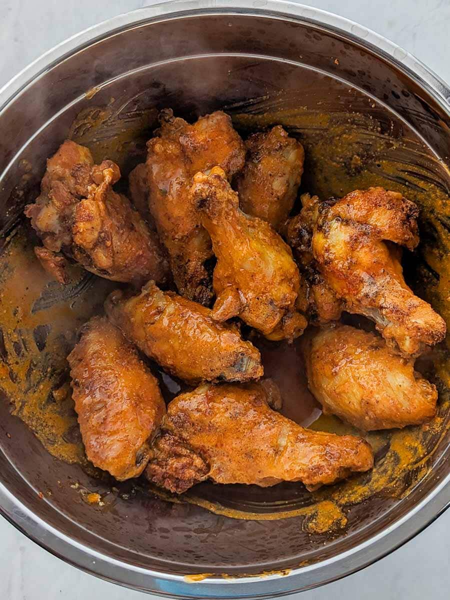 Chicken wings in a pot with sauce.