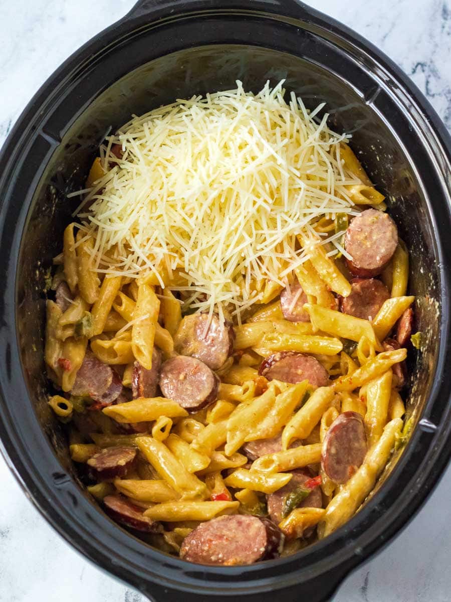 A crock pot filled with pasta and sausage.