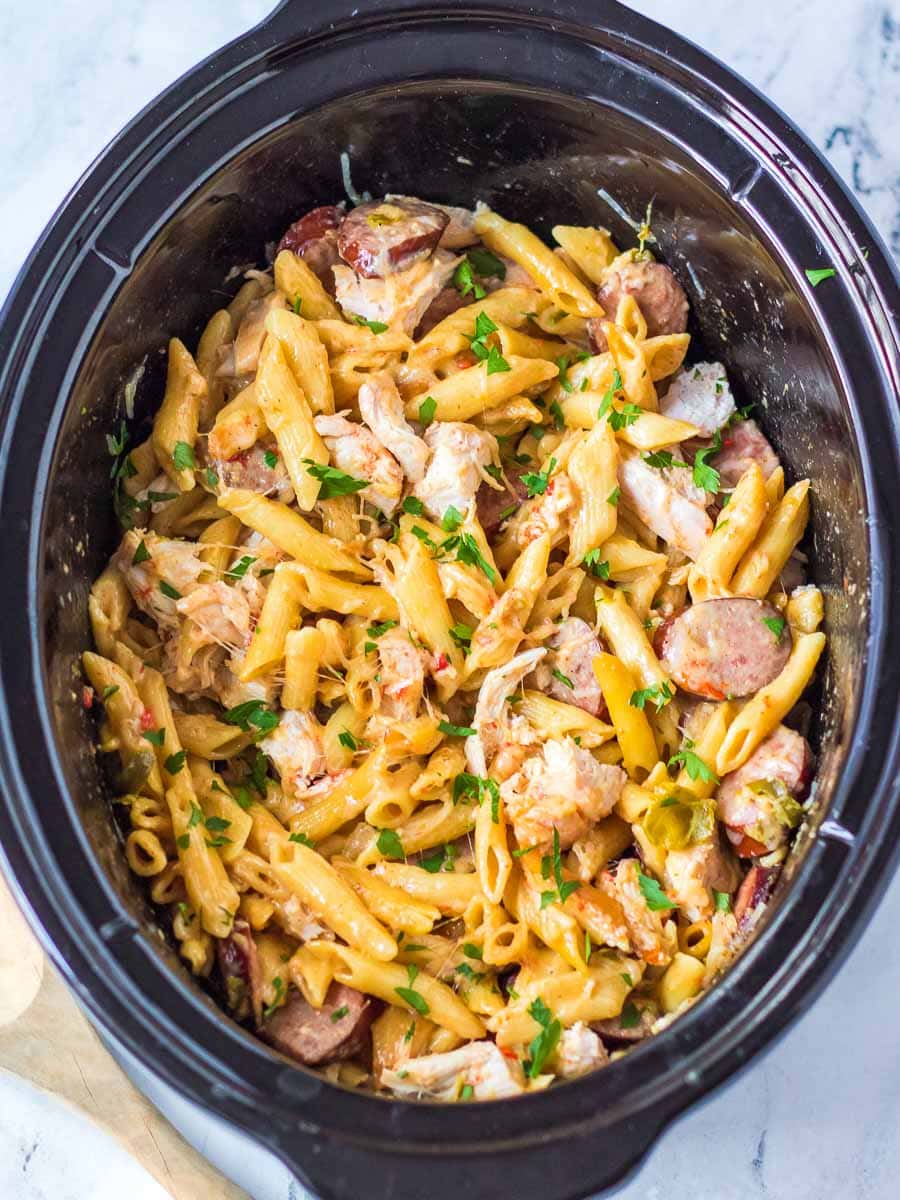 A crock pot filled with pasta and chicken.