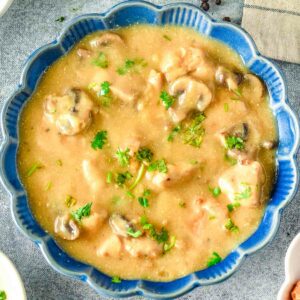 Chicken stroganoff soup with mushrooms in a blue bowl.