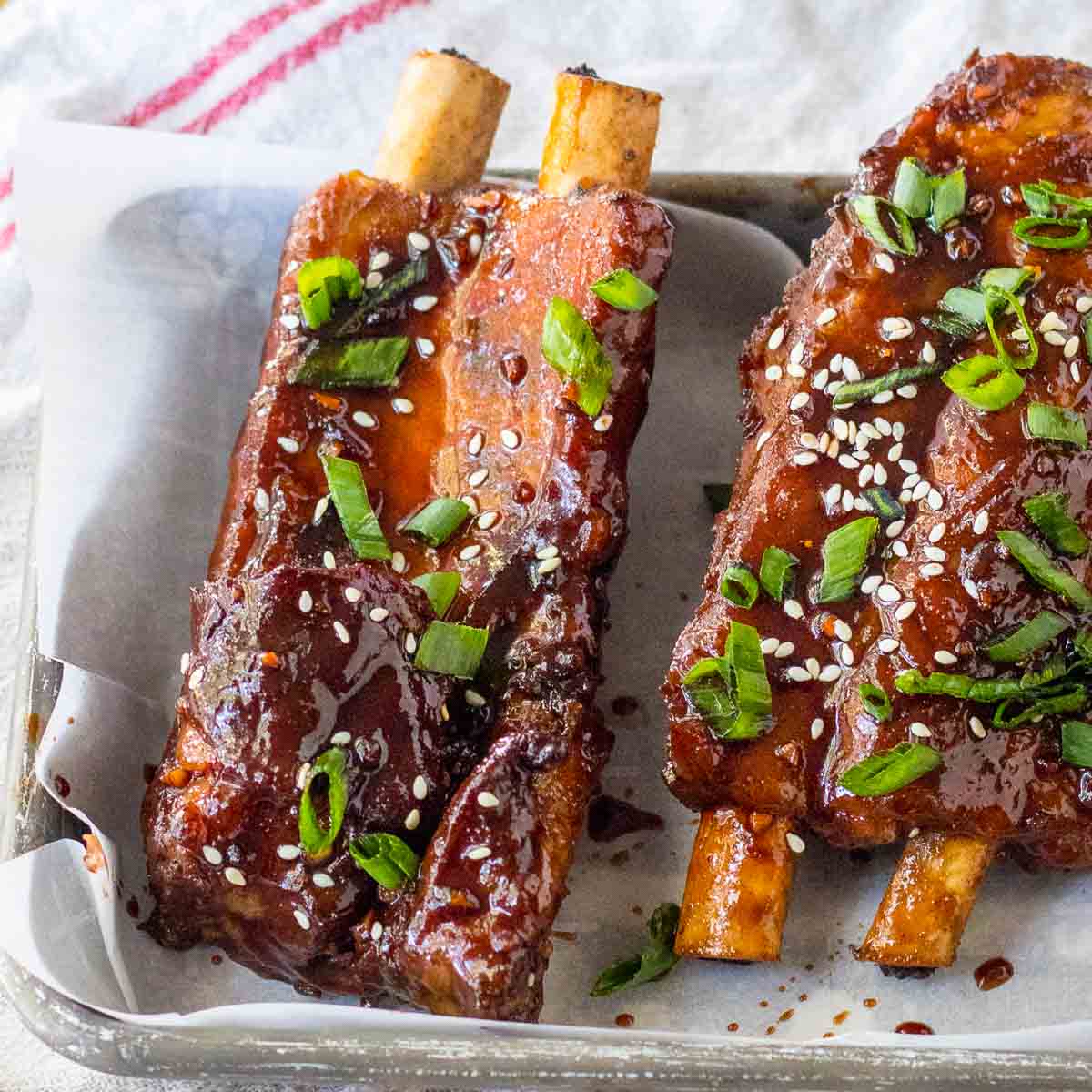 Two ribs on a tray with sesame seeds and green onions.