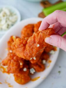 Buffalo wings on a plate with blue cheese and celery.