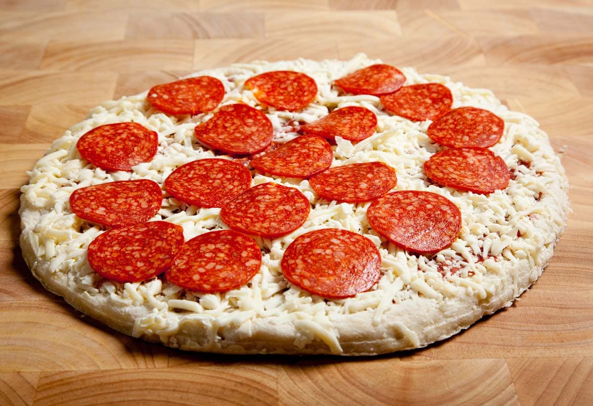 An upgraded pepperoni pizza on a rustic wooden cutting board.