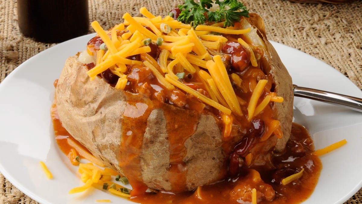 A baked potato topped with cheese and sauce.