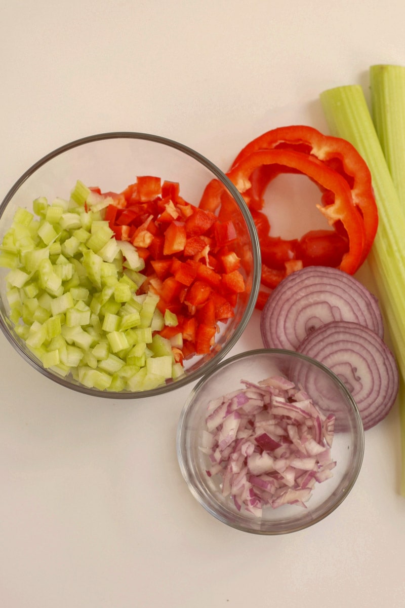 Celery, onion, carrots and celery in bowls.