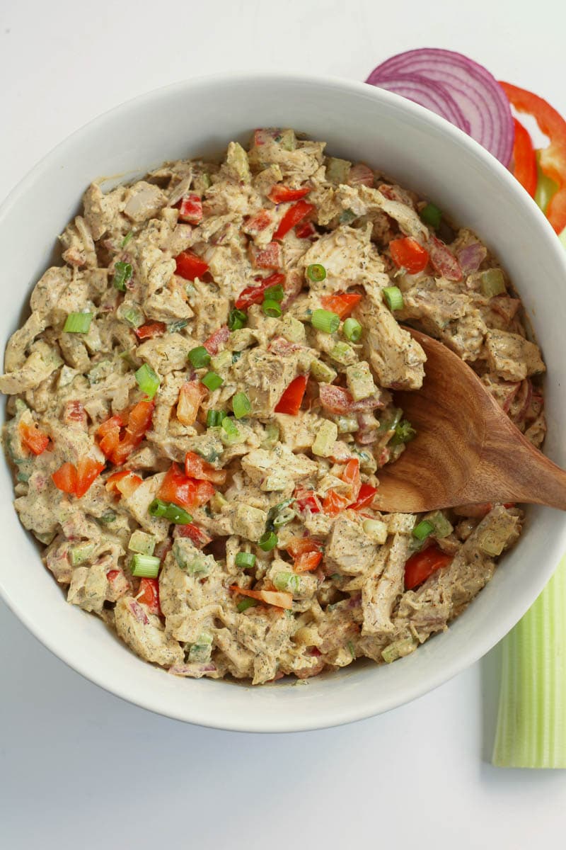 Chicken salad in a white bowl with celery and carrots.
