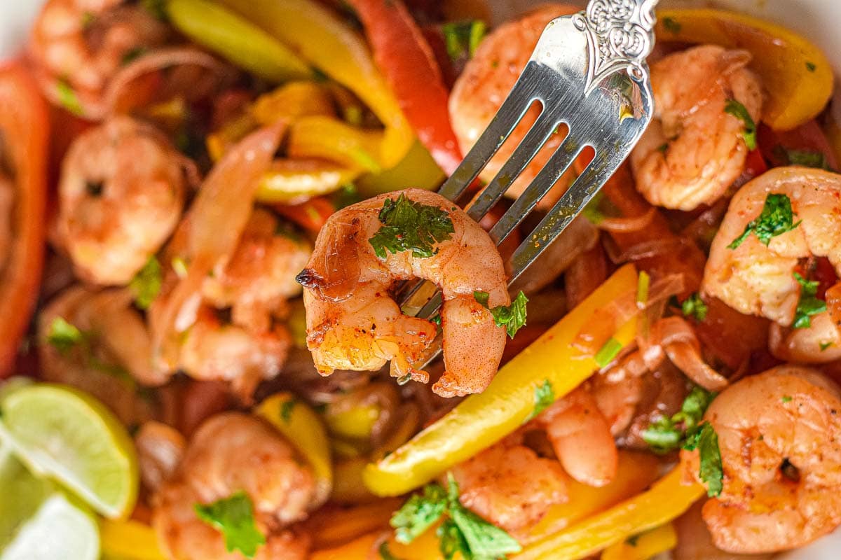 Shrimp and peppers on a plate with a fork.