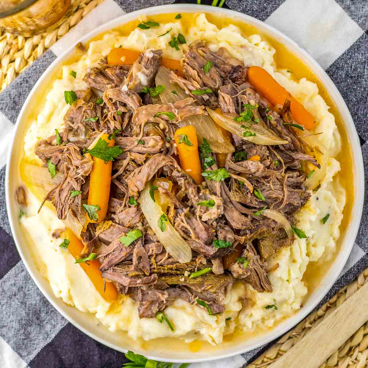 A plate of pot roast with carrots and mashed potatoes.