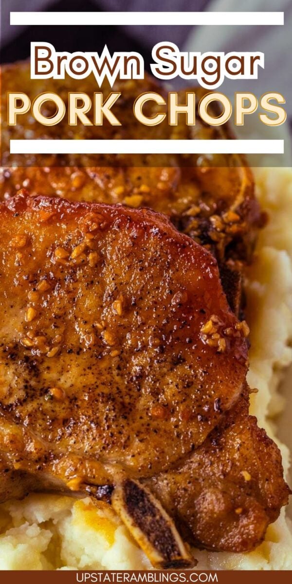 Close-up of two juicy brown sugar pork chops with seasoning, served atop a creamy bed of mashed potatoes.