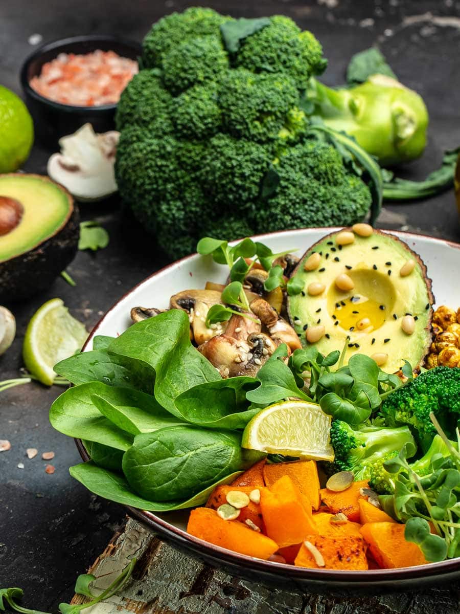 A bowl of vegetables with avocado, kale, and broccoli.