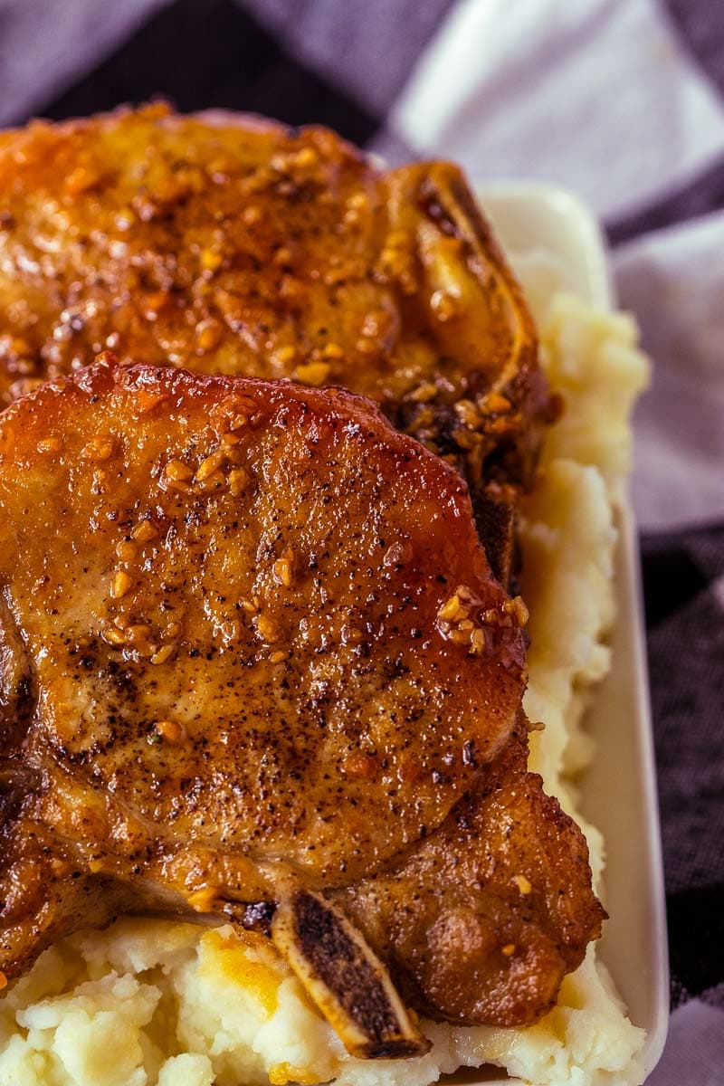 Pork chops on a plate with mashed potatoes.