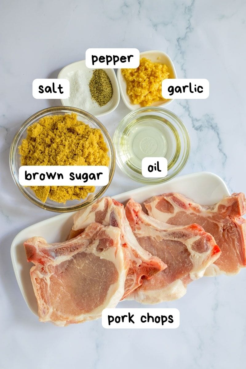 Ingredients for pork chops on a white plate.