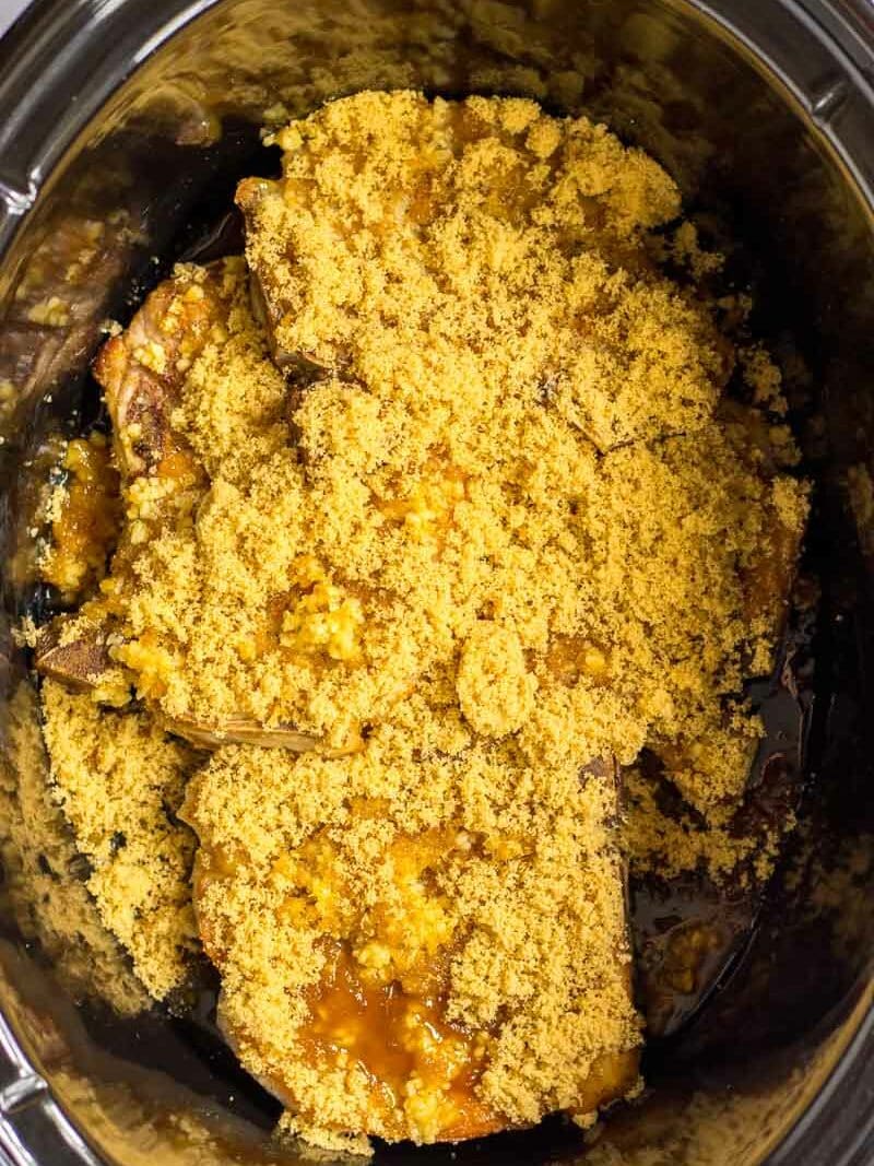A crock pot filled with a mixture of meat and breadcrumbs.