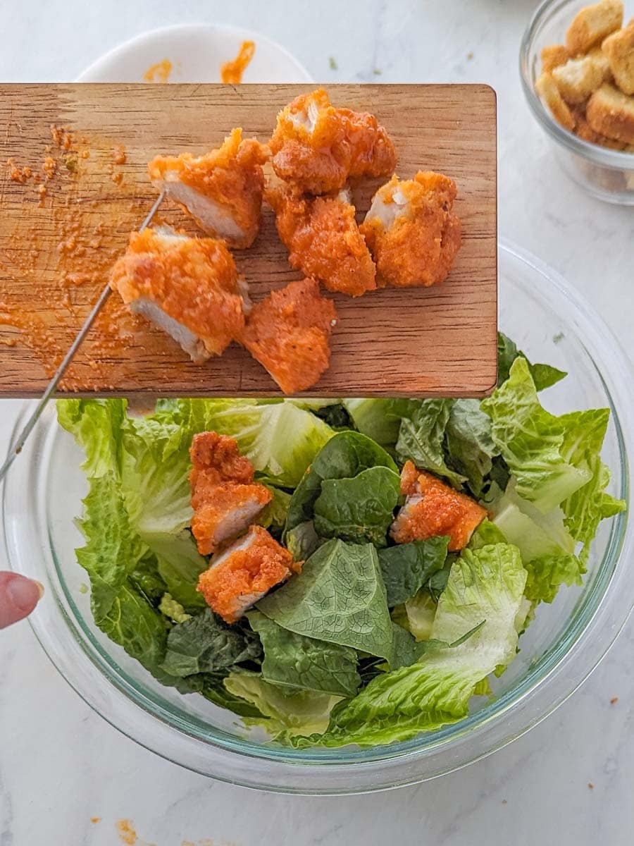 Tossing the chopped chicken in a salad.