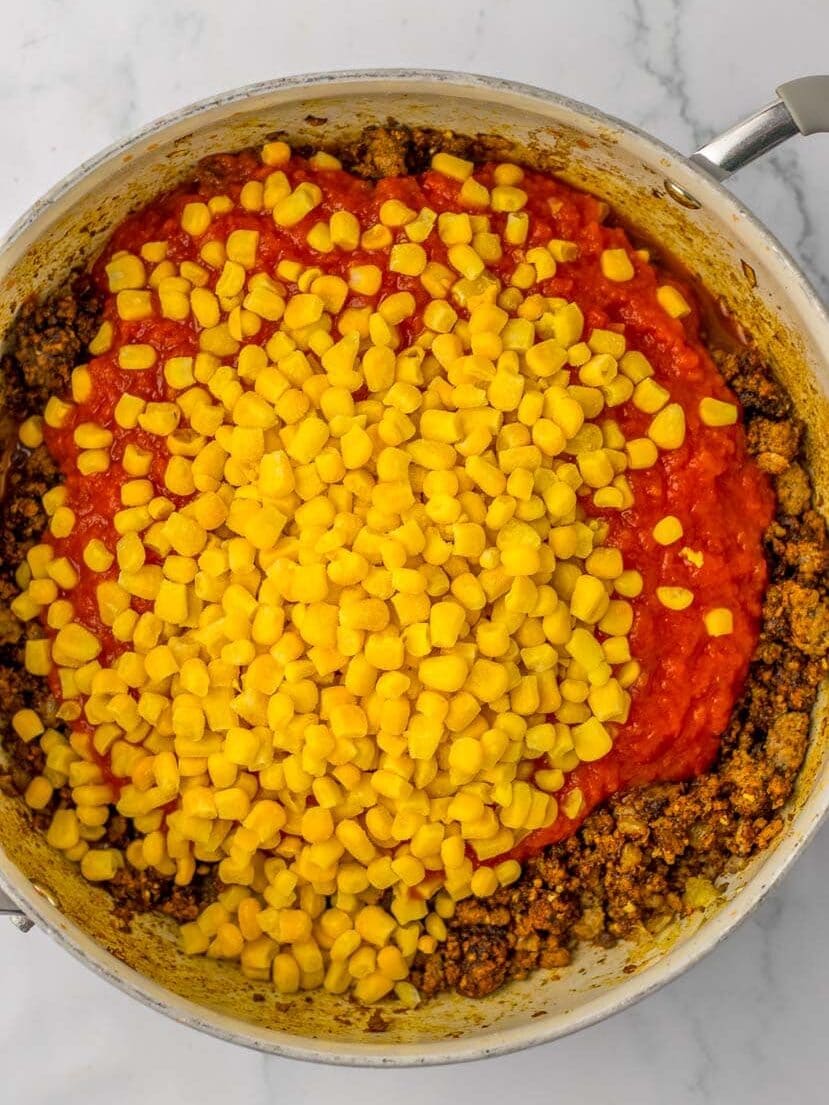 A skillet filled with meat, corn and tomatoes.