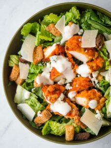 A bowl of chicken salad with croutons and dressing.