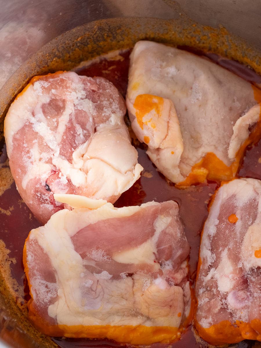 Pork chops in a pot with sauce.