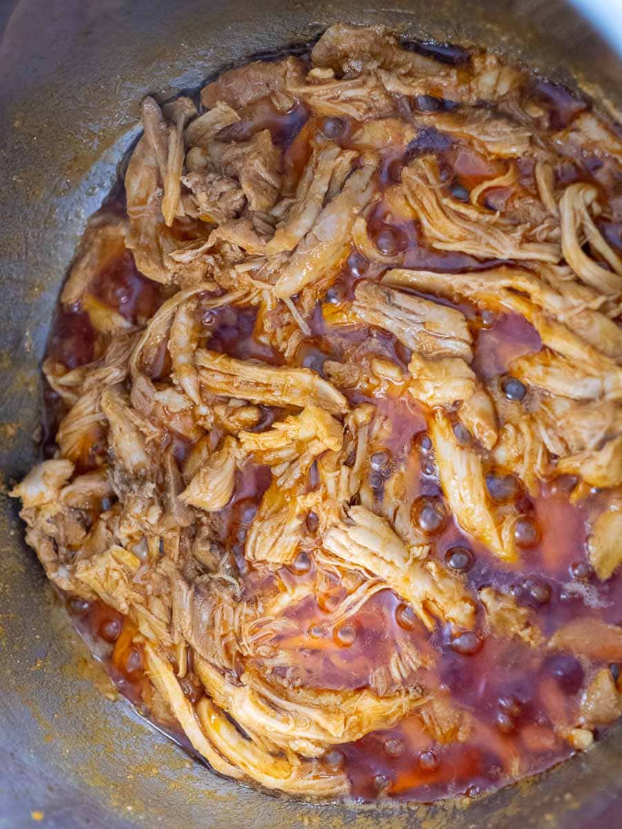 Shredded chicken in a pot with sauce.