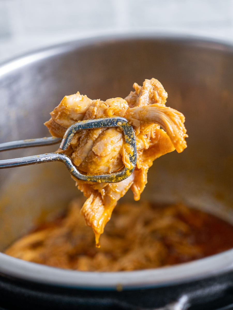A fork is being used to remove chicken from a pot.