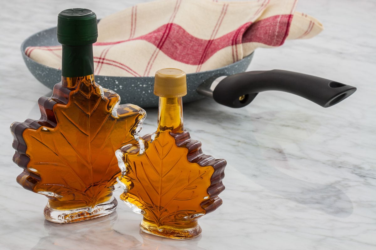 Maple syrup in a glass bottle on a marble counter.
