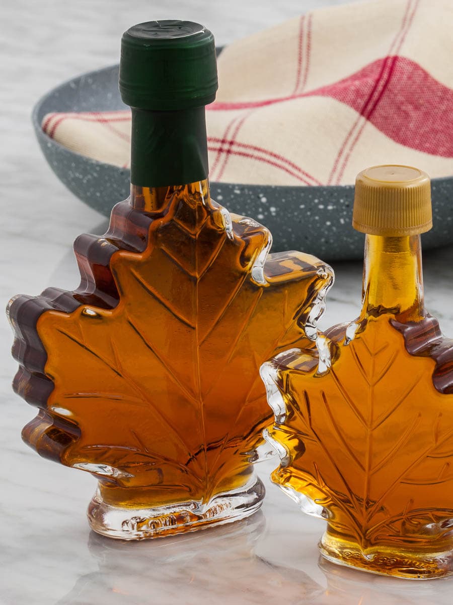 Two maple syrup bottles on a table.