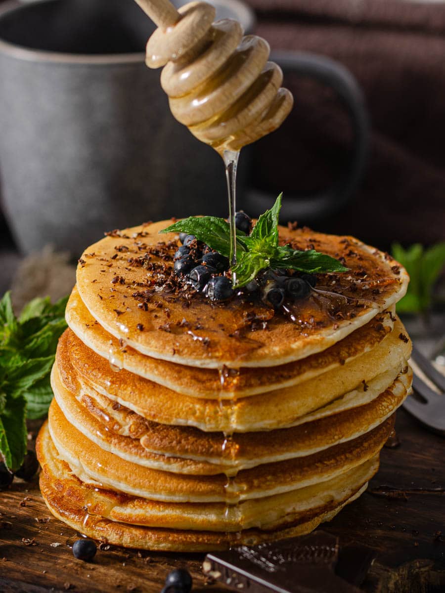 A stack of pancakes with maple syrup and blueberries.