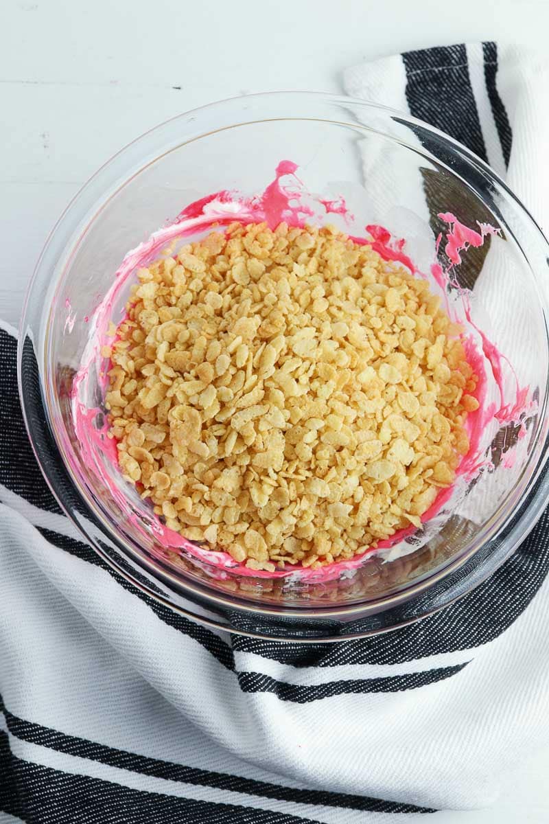 A bowl filled with graham cracker crumbs and pink frosting.