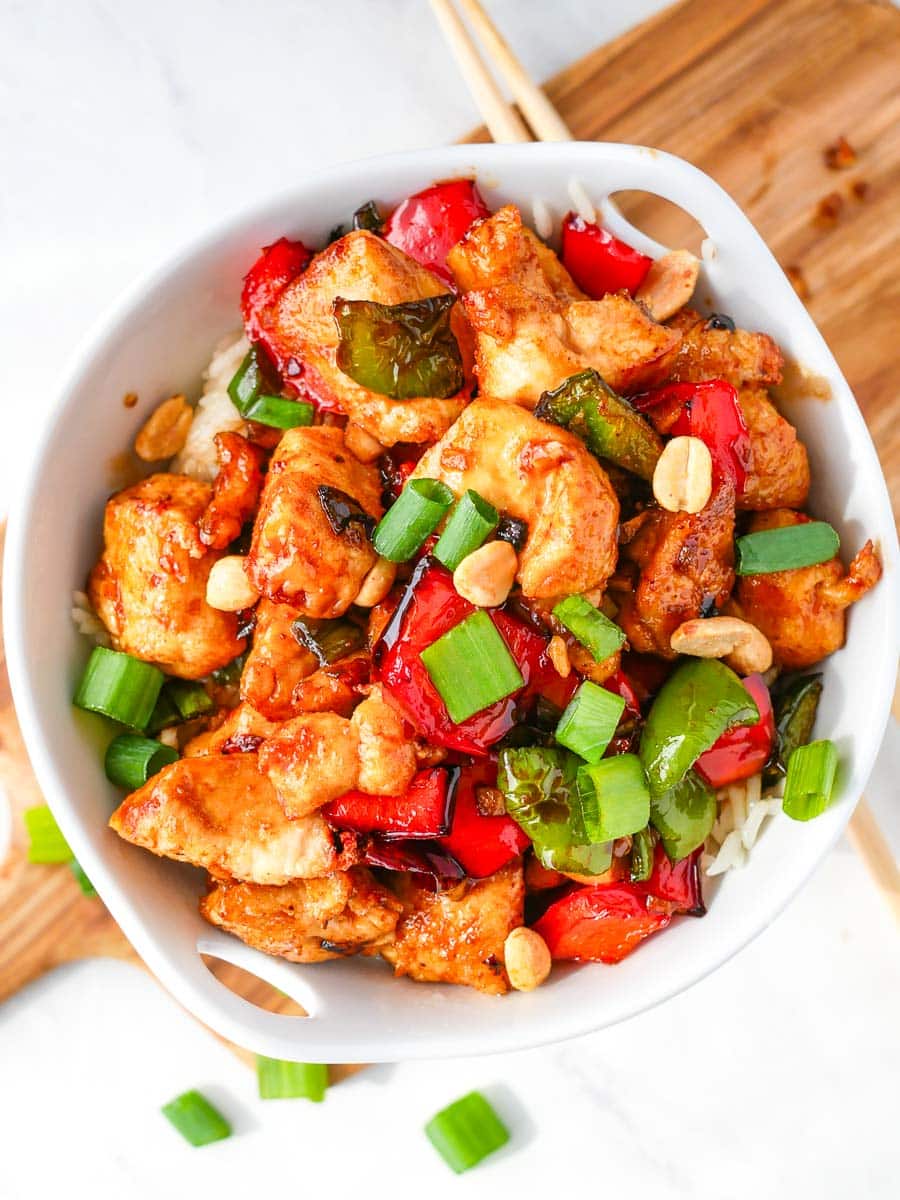 Kung Pao Chicken with peppers and peanuts in a white bowl.