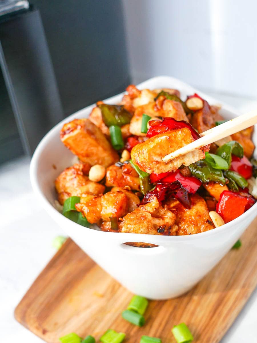 Kung Pao Chicken in a white bowl with chopsticks.